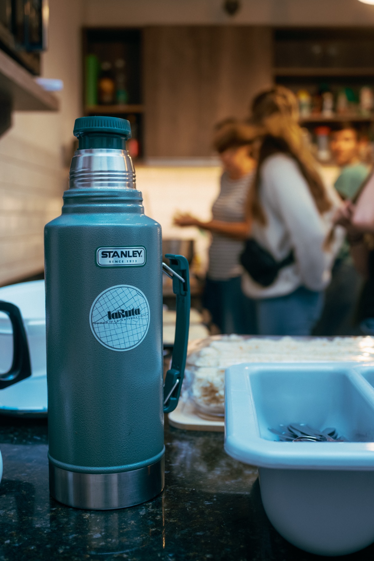 Un termo verde en la cocina mientras la gente prepara la merienda