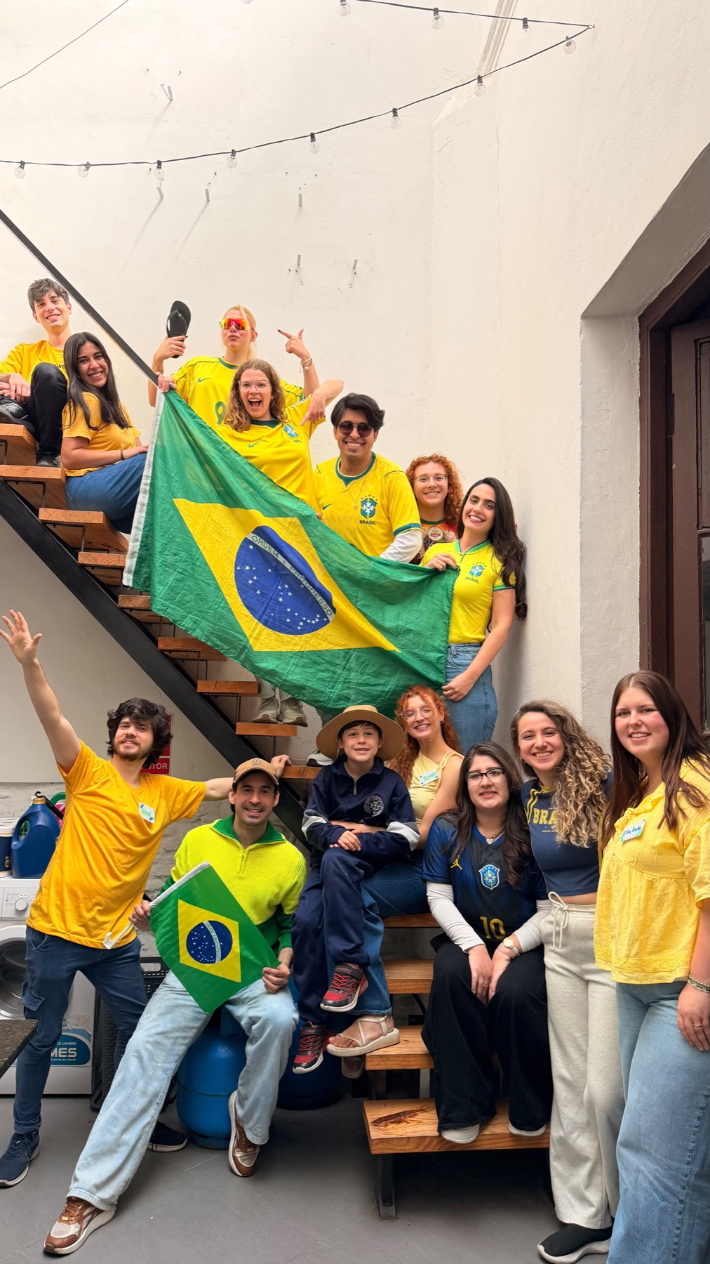 Estudiantes con camisetas y banderas de Brasil mirando un partido juntos en la casa